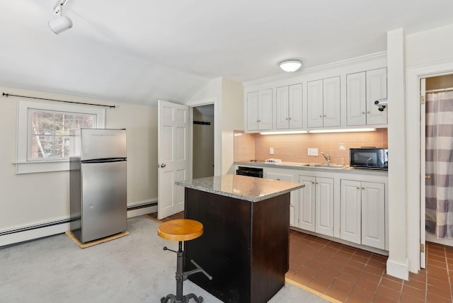 kitchen with tasteful backsplash, white cabinets, a kitchen island, freestanding refrigerator, and black microwave