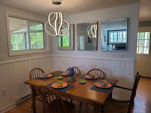 dining room with a wainscoted wall, a chandelier, baseboard heating, and wood finished floors