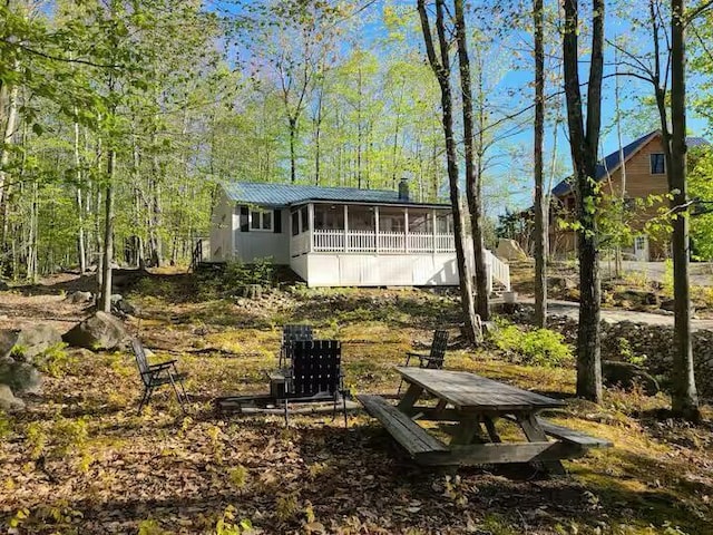 rear view of property featuring a sunroom, metal roof, and stairway