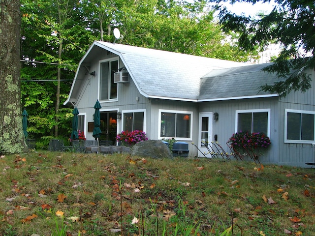 view of front of house featuring a gambrel roof and a wall mounted AC