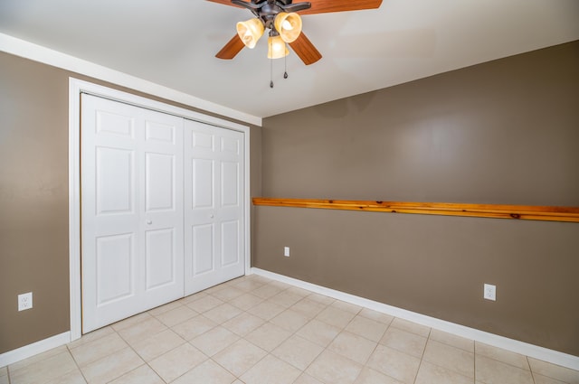 unfurnished bedroom with a closet, baseboards, light tile patterned flooring, and a ceiling fan