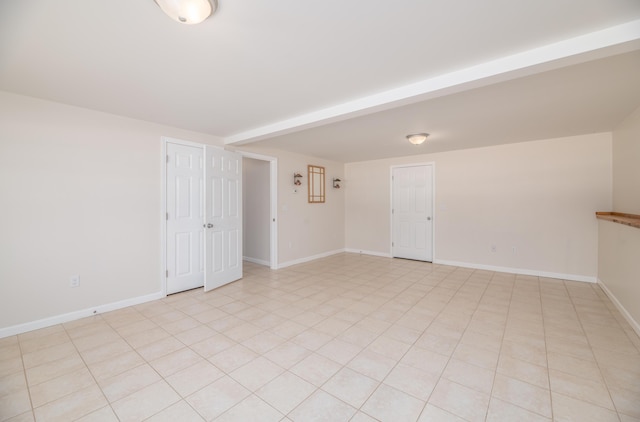 spare room featuring light tile patterned floors and baseboards