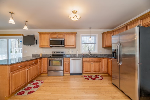 kitchen with a peninsula, brown cabinets, appliances with stainless steel finishes, and a sink