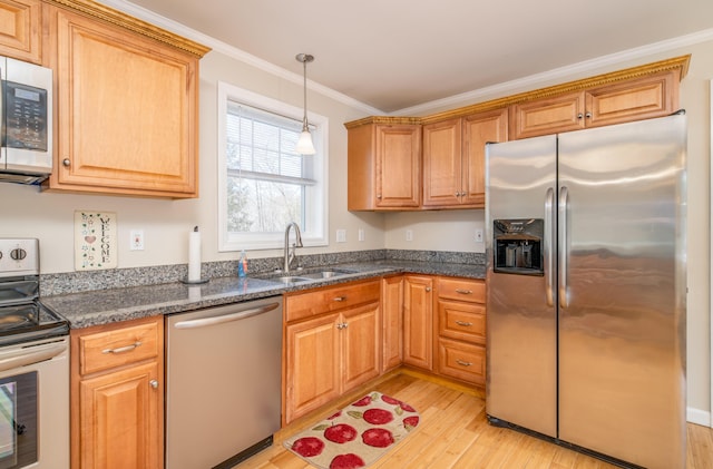 kitchen with a sink, hanging light fixtures, stainless steel appliances, light wood-style floors, and crown molding