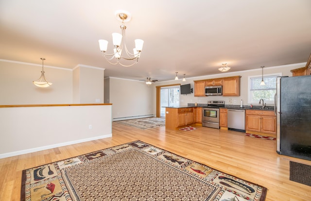 kitchen featuring dark countertops, a baseboard heating unit, crown molding, light wood-style flooring, and appliances with stainless steel finishes