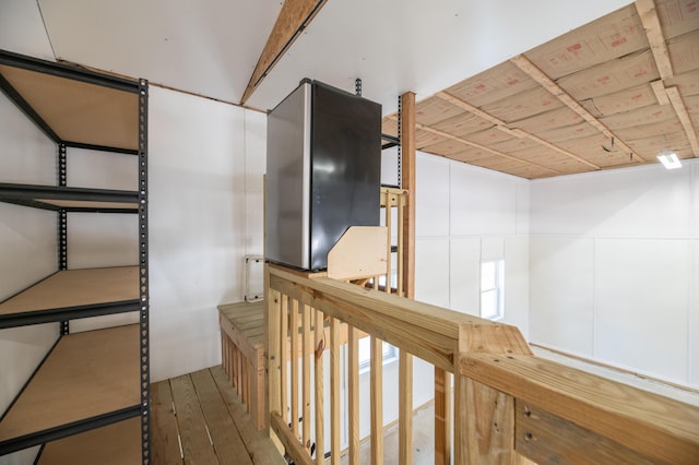 corridor with wood finished floors and an upstairs landing