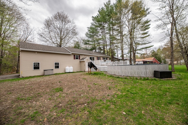 rear view of property featuring a pool, a wooden deck, and a lawn
