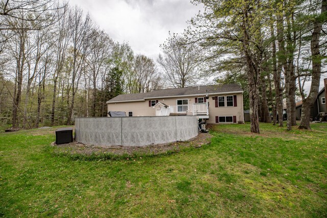 back of house with central AC unit, a wooden deck, and a lawn