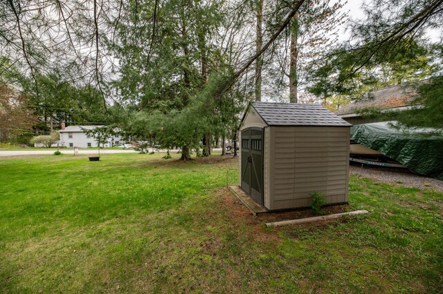view of green lawn featuring a storage shed and an outbuilding