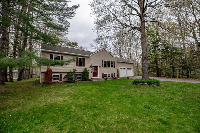bi-level home featuring driveway, an attached garage, and a front lawn