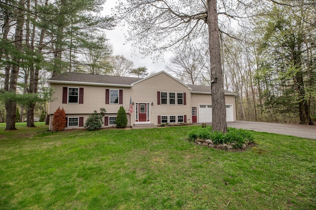 split foyer home with asphalt driveway, an attached garage, and a front yard