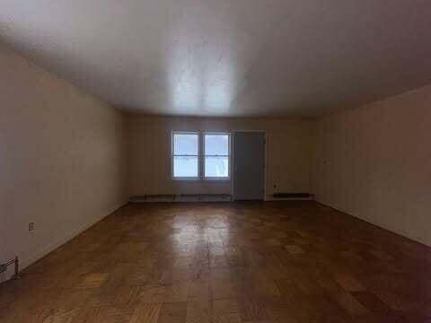 unfurnished room with baseboard heating and wood finished floors