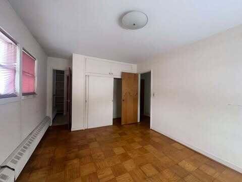 unfurnished bedroom with baseboard heating and a closet