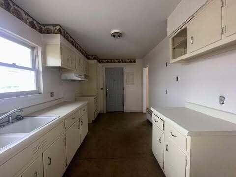 kitchen featuring white cabinets, light countertops, and a sink