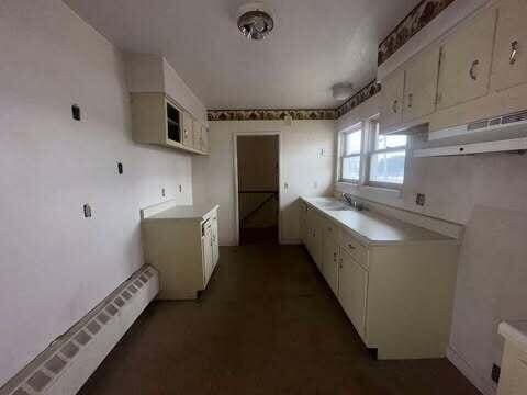 kitchen featuring white cabinetry, a baseboard heating unit, light countertops, and a sink