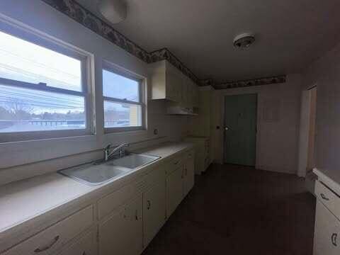 kitchen with light countertops, white cabinets, and a sink