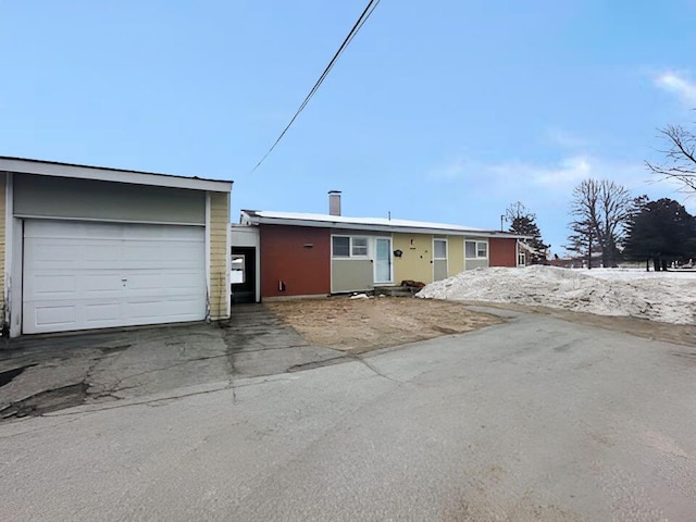 ranch-style home with a garage and aphalt driveway