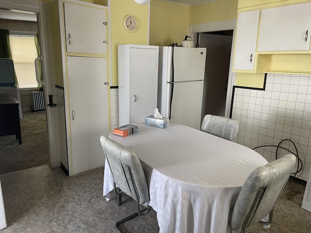 dining area with carpet flooring, tile walls, and radiator heating unit