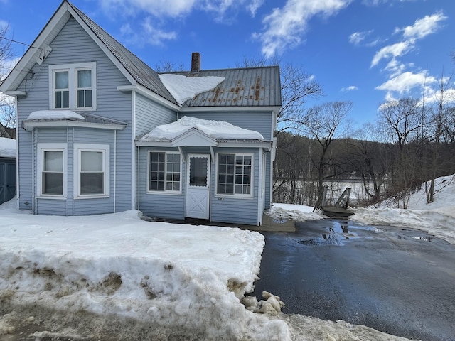 snow covered rear of property featuring a chimney