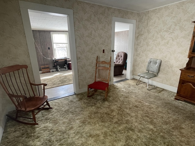 living area featuring baseboards, carpet, and crown molding