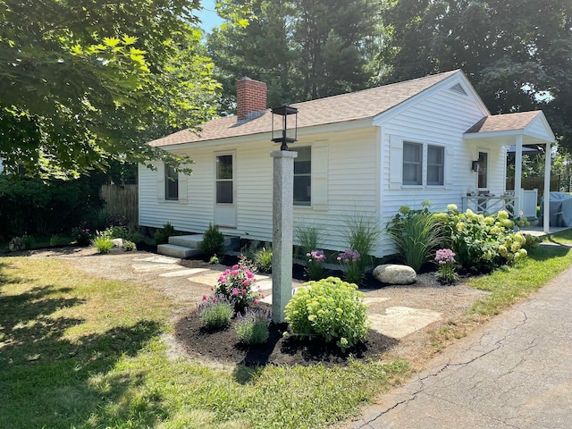 exterior space featuring roof with shingles, a chimney, and a front lawn