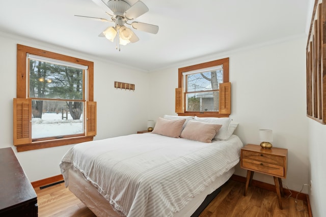 bedroom with ceiling fan, crown molding, baseboards, and wood finished floors