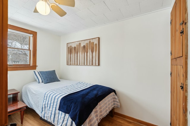 bedroom with a ceiling fan, baseboards, and wood finished floors