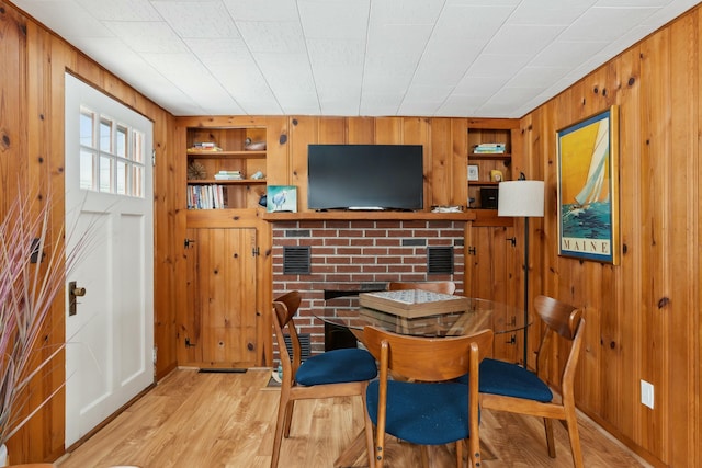 dining area featuring built in shelves, light wood-style flooring, and wooden walls