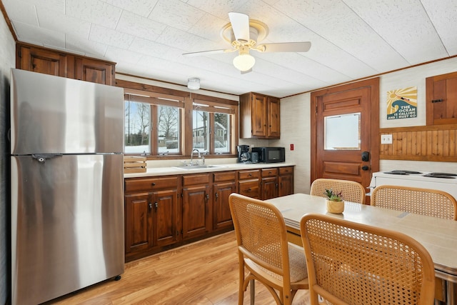 kitchen featuring light wood-style flooring, a sink, light countertops, freestanding refrigerator, and brown cabinets