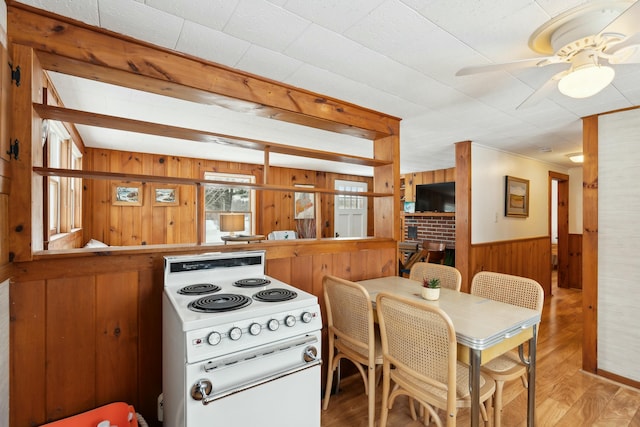 kitchen with ceiling fan, wood walls, wood finished floors, wainscoting, and white electric range oven