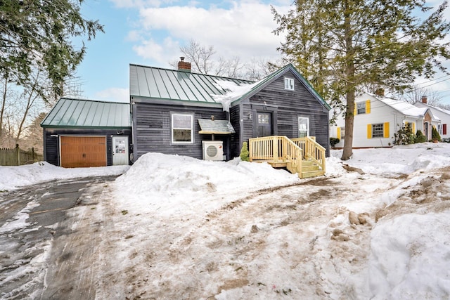 view of front of home with a garage, a standing seam roof, a chimney, and metal roof