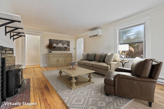 living area featuring ornamental molding, arched walkways, hardwood / wood-style flooring, and a wall mounted AC