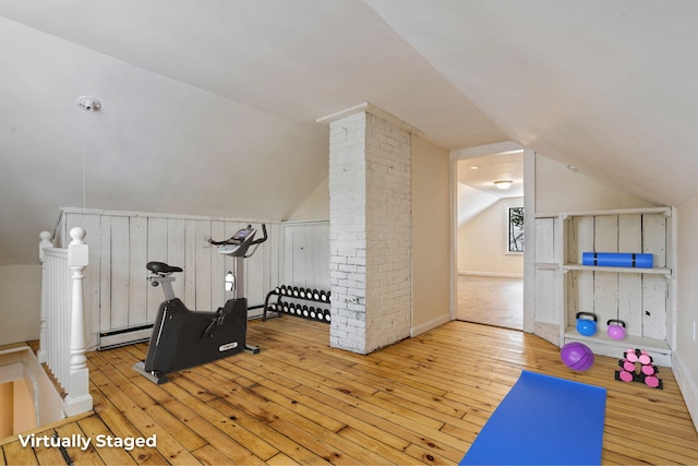 exercise room featuring lofted ceiling, a baseboard heating unit, light wood finished floors, and ornate columns