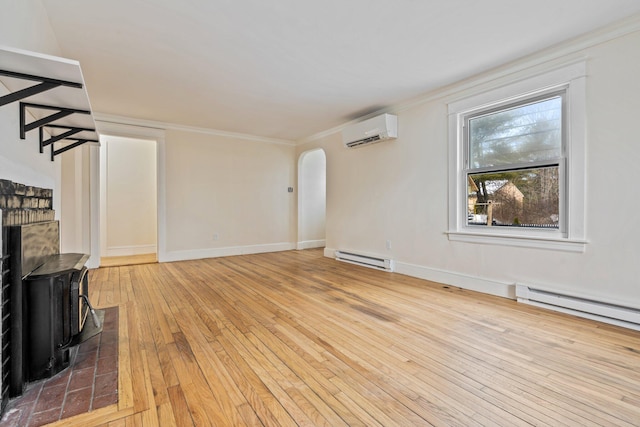 unfurnished living room with arched walkways, an AC wall unit, ornamental molding, baseboard heating, and light wood-type flooring