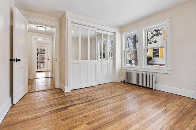 interior space featuring radiator heating unit, light wood-style flooring, and baseboards