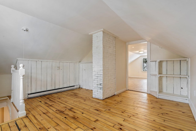 additional living space featuring light wood-style floors, lofted ceiling, decorative columns, and baseboard heating