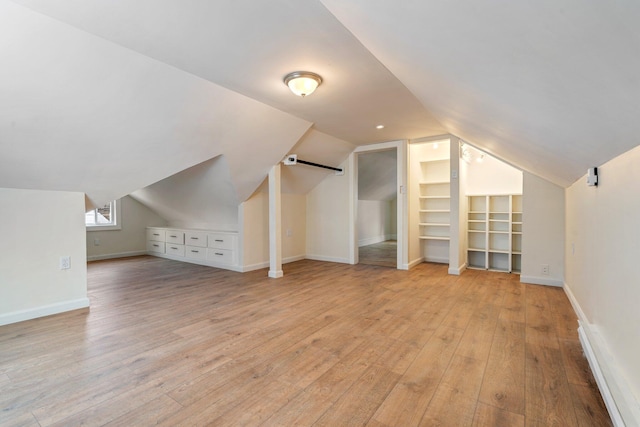 additional living space featuring lofted ceiling, light wood-style flooring, and baseboards