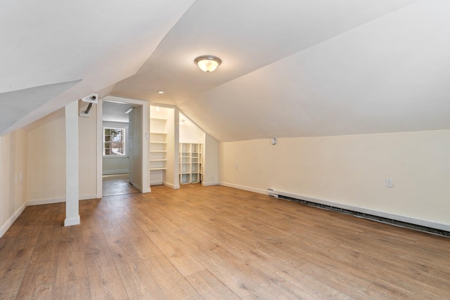 additional living space with lofted ceiling, light wood-style flooring, baseboards, and a baseboard radiator