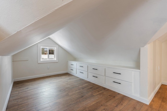 bonus room featuring dark wood-style floors, vaulted ceiling, and baseboards