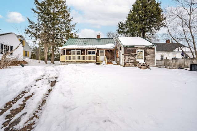 view of front of property with metal roof, a porch, a chimney, and fence