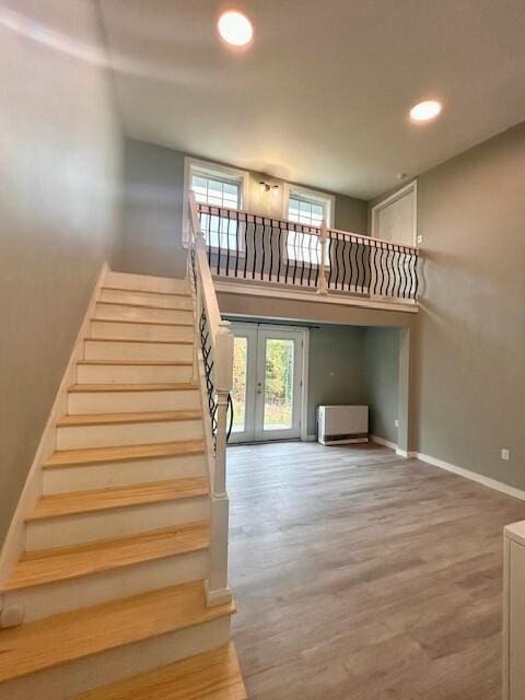 stairway featuring french doors, wood finished floors, a wealth of natural light, and baseboards