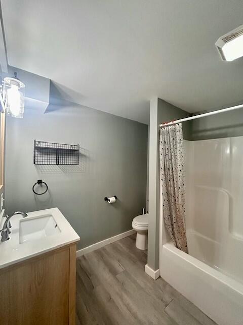 full bathroom with baseboards, visible vents, toilet, wood finished floors, and vanity