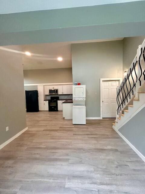 unfurnished living room featuring recessed lighting, washer / clothes dryer, baseboards, stairs, and light wood finished floors