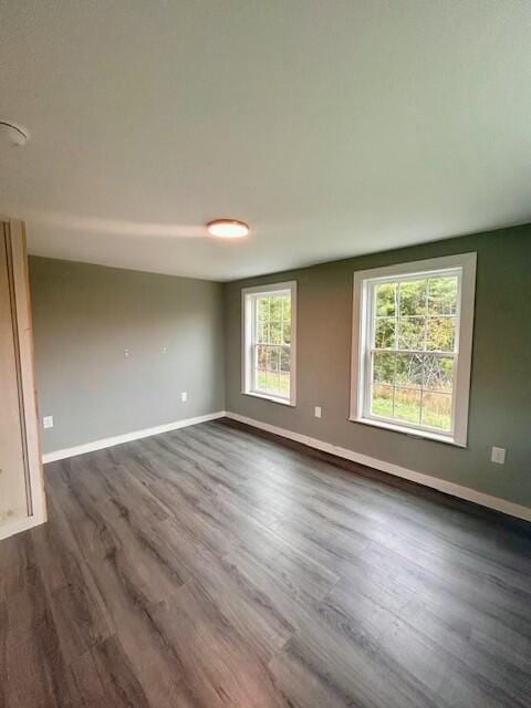 unfurnished room with dark wood-type flooring and baseboards