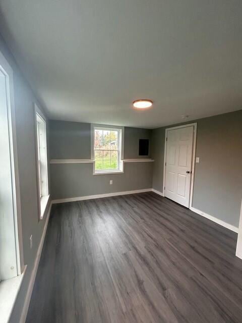 spare room featuring baseboards and dark wood-style flooring