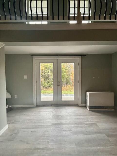 interior space featuring a towering ceiling, baseboards, wood finished floors, and french doors