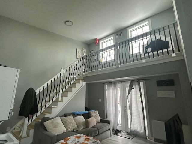 living room with stairway, french doors, a towering ceiling, and wood finished floors