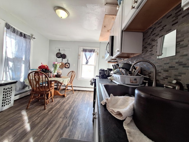 kitchen with dark wood-style floors, white cabinetry, baseboard heating, and stainless steel microwave