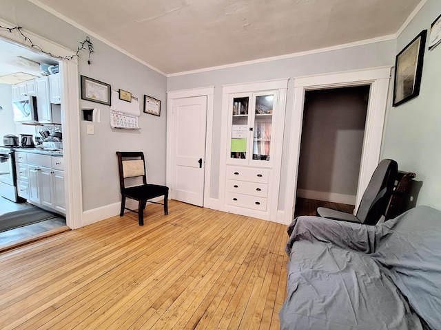 bedroom featuring light wood finished floors, baseboards, and crown molding