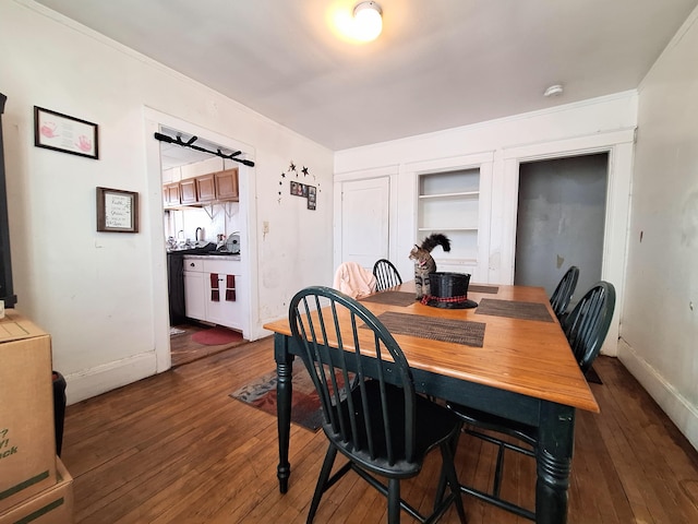 dining space featuring built in features, dark wood finished floors, and baseboards